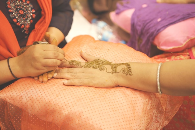 Foto middelsnede van een vrouw die een henna-tattoo maakt op de hand van een vriend