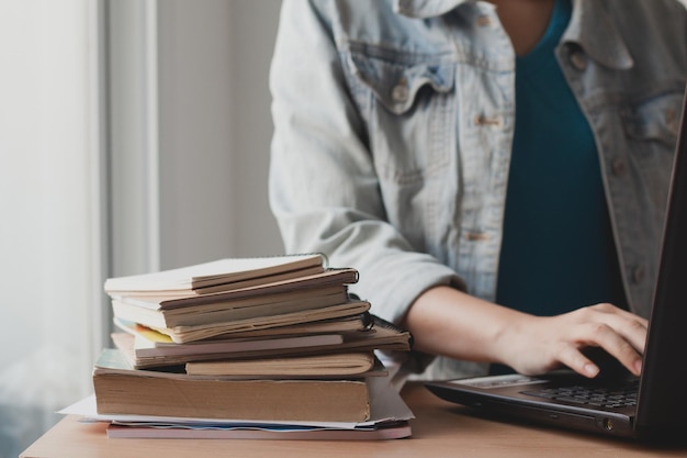 Middelsnede van een vrouw die een laptop gebruikt bij boeken op tafel