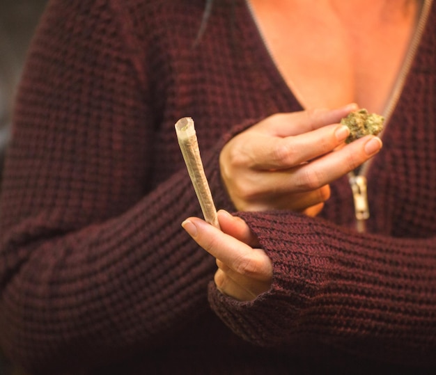 Foto middelsnede van een vrouw die een marihuana joint vasthoudt