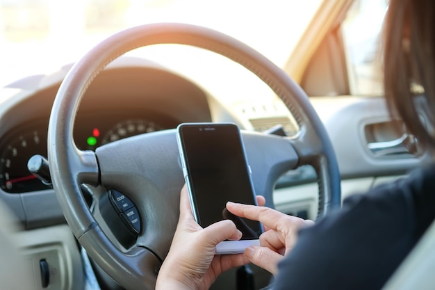 Middelsnede van een vrouw die een smartphone gebruikt in de auto