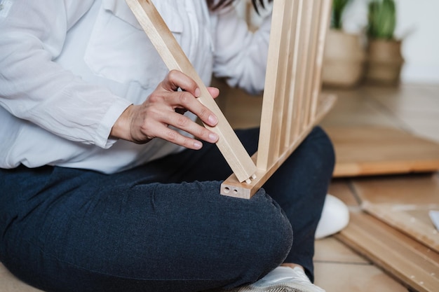 Middelsnede van een vrouw die houten meubels thuis vasthoudt