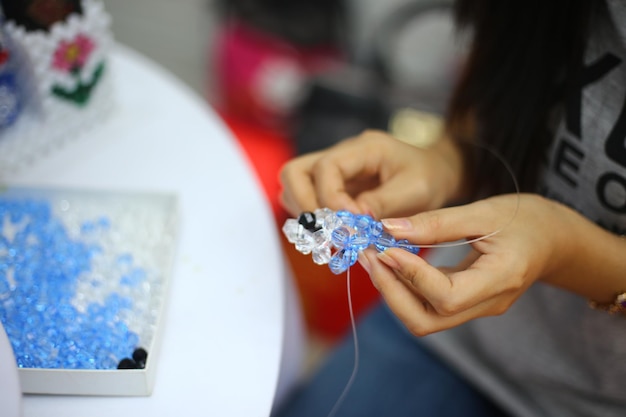 Foto middelsnede van een vrouw die kristallen sieraden maakt in een werkplaats