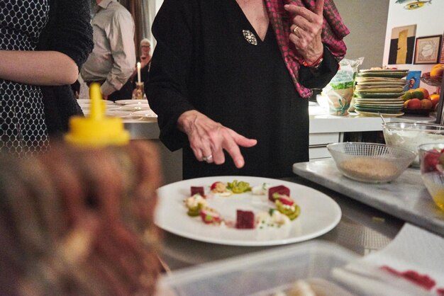 Foto middelsnede van een vrouw die naar voedsel in een bord op tafel wijst