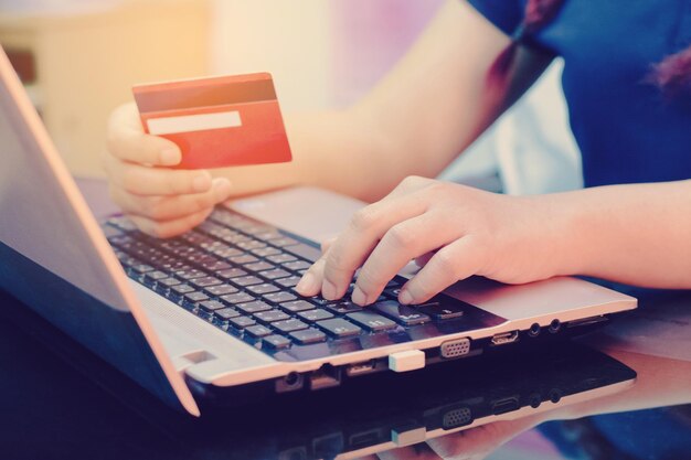 Middelsnede van een vrouw die online winkelt via een laptop aan tafel