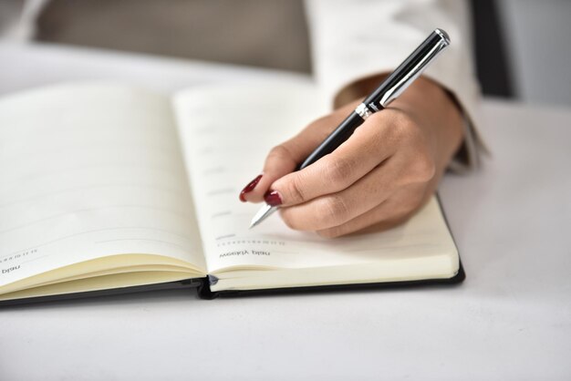 Middelsnede van een vrouw die op een boek op tafel schrijft