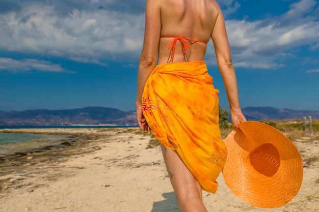 Middelsnede van een vrouw die op het strand tegen de lucht staat