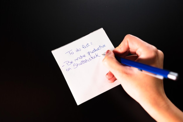 Foto middelsnede van een vrouw die papier vasthoudt op een zwarte achtergrond