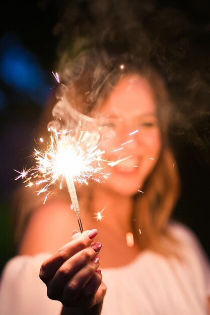 Foto middelsnede van een vrouw die's nachts een vonkjeslampje vasthoudt