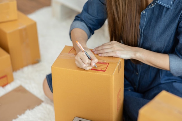 Middelsnede van een vrouw die thuis op een kartonnen doos schrijft