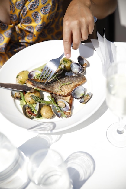 Middelsnede van een vrouw die vis van zeevruchten op een bord eet