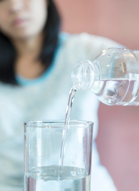 Middelsnede van een vrouw die water in een glas giet