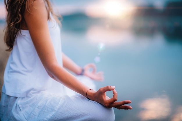 Foto middelsnede van een vrouw die yoga doet terwijl ze op een pier bij het meer zit