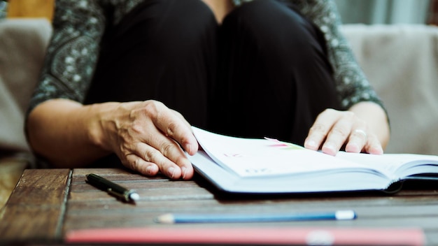 Middelsnede van een vrouw met een boek aan tafel
