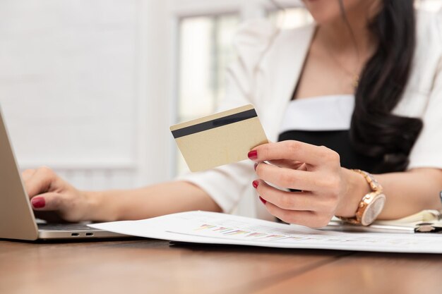 Middelsnede van een vrouw met een creditcard terwijl ze een laptop op kantoor gebruikt