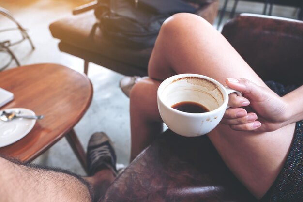 Foto middelsnede van een vrouw met een koffiekop op tafel