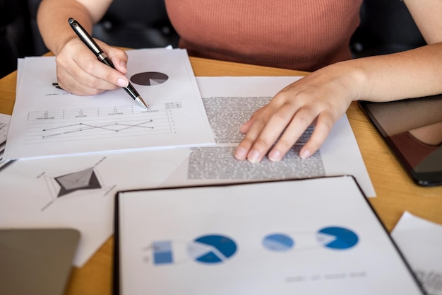 Middelsnede van een zakenvrouw die aan grafieken werkt aan haar bureau in het kantoor