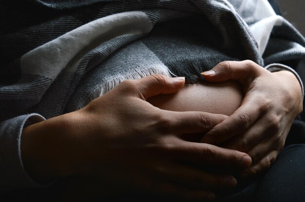 Foto middelsnede van een zwangere vrouw die thuis haar buik vasthoudt