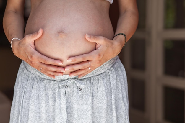 Middelsnede van een zwangere vrouw die thuis staat