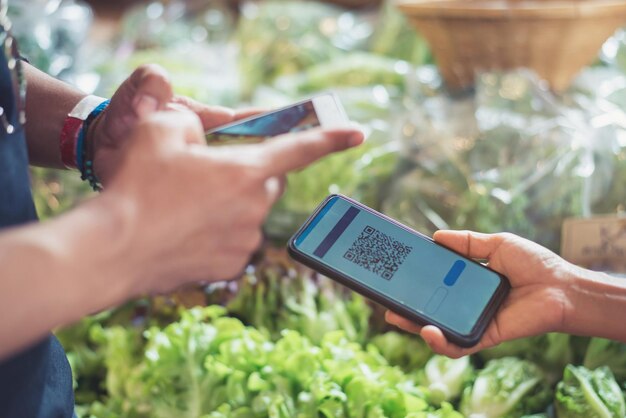 Middelsnede van persoon die mobiele telefoon gebruikt op de markt