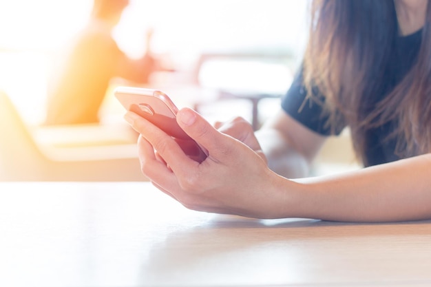 Middelsnede van vrouw met mobiele telefoon aan tafel