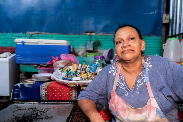 Foto midden-amerikaanse vrouw die op een markt in nicaragua aan haar pakje frisdrank en snoep werkt