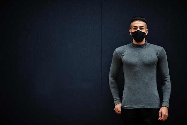 Midden-Oosten man in grijze coltrui en zwart gezicht beschermen masker op geïsoleerde achtergrond