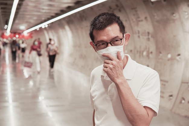 Midden oude Aziatische mens die glazen en medisch gezichtsmasker, Wuhan-coronavirusuitbarsting, luchtvervuiling en gezondheidsconcept dragen