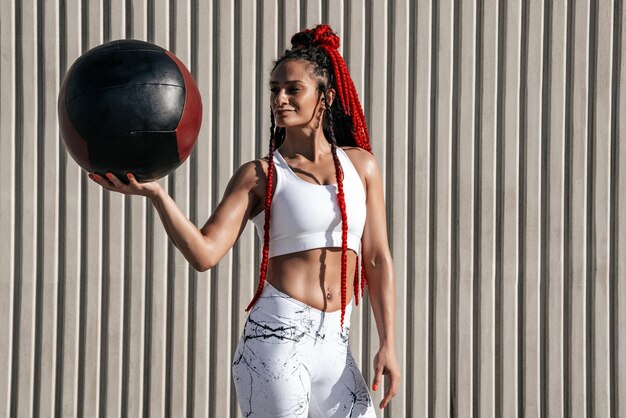 Middenplan Atletische vrouw met med ball Kracht en motivatie Foto van sportieve vrouw in modieuze sportkleding