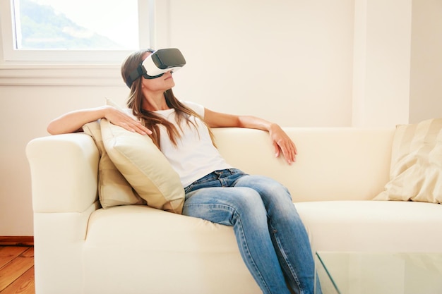 Middenvolwassen vrouw die thuis een virtuele realiteitsstimulator gebruikt.