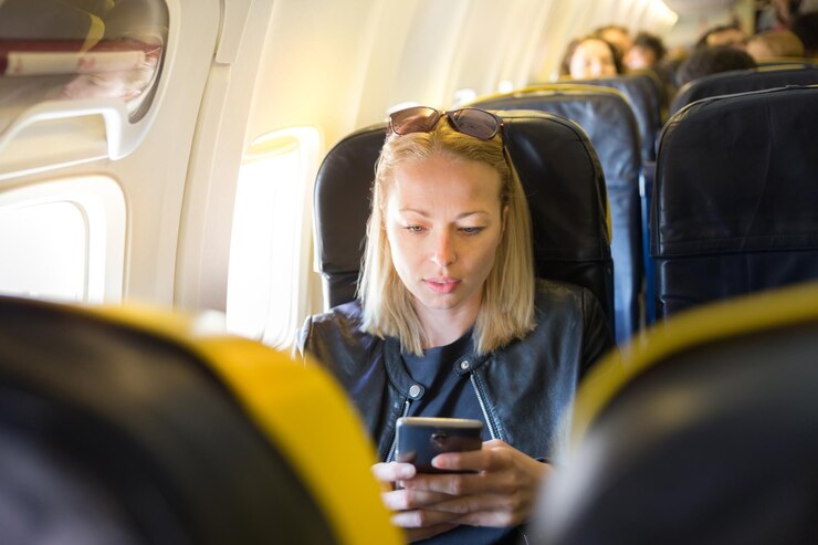 Foto middenvolwassen vrouw met een smartphone terwijl ze in het vliegtuig zit
