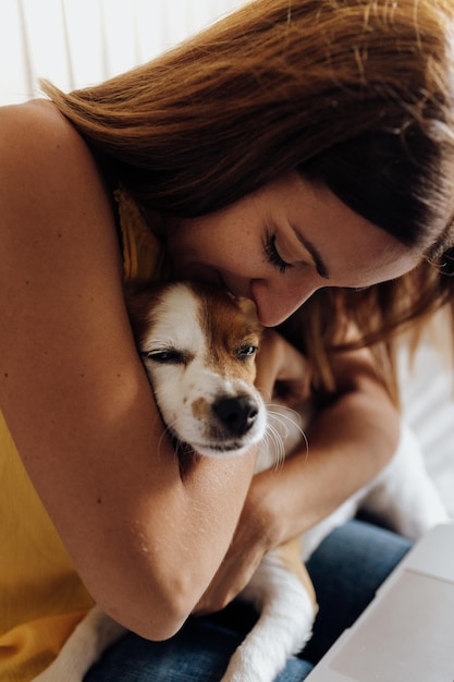 Middenvolwassen vrouw omhelst hond thuis