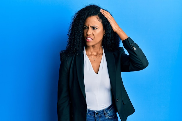 Middle age african american woman wearing business clothes confuse and wonder about question uncertain with doubt thinking with hand on head pensive concept