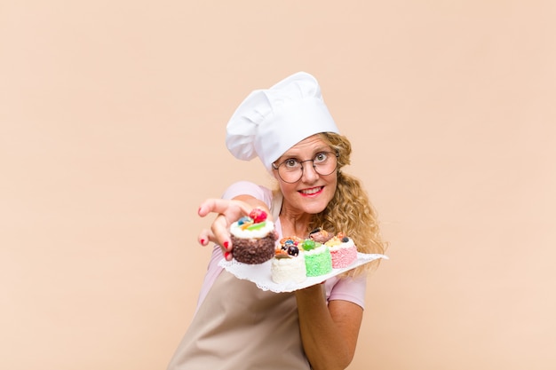 Middle age baker woman cooking cakes