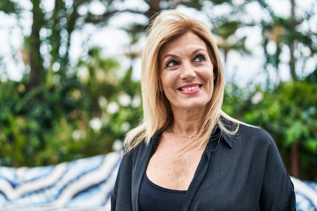 Middle age blonde woman smiling confident standing at street