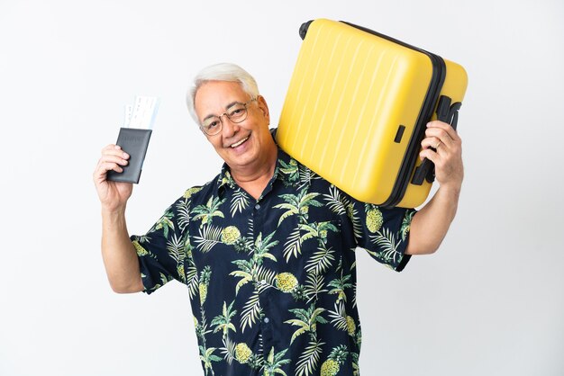 Middle age Brazilian man isolated on white background in vacation with suitcase and passport