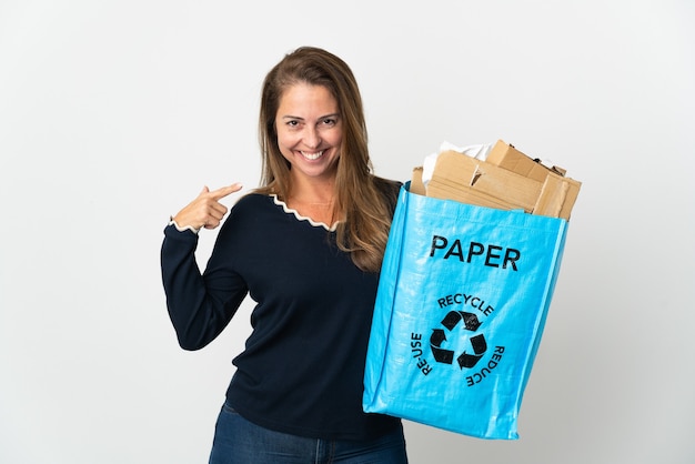 Middle age brazilian woman holding a recycling bag full of paper to recycle over isolated wall giving a thumbs up gesture