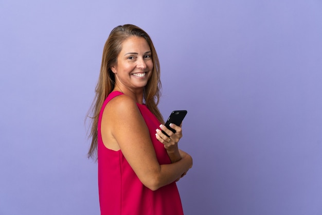 Middle age brazilian woman isolated on holding a mobile phone and with arms crossed