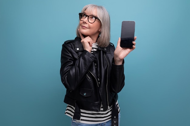 Middle age business smart modern s modern old woman with gray hair demonstrates a smartphone with a