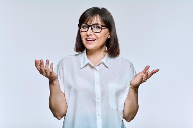 Middle age business woman in glasses talking looking at camera on light background