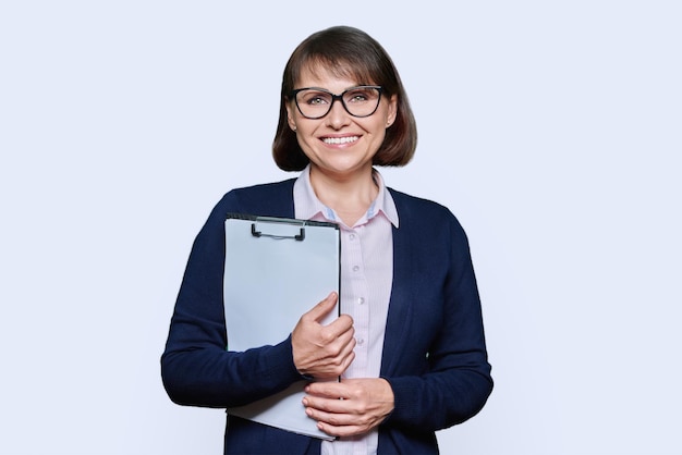 Middle age business woman with clipboard looking at camera on white background