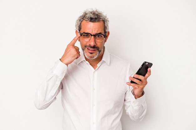 人差し指で失望のジェスチャーを示す白い背景で隔離の携帯電話を保持している中年白人ビジネスマン。