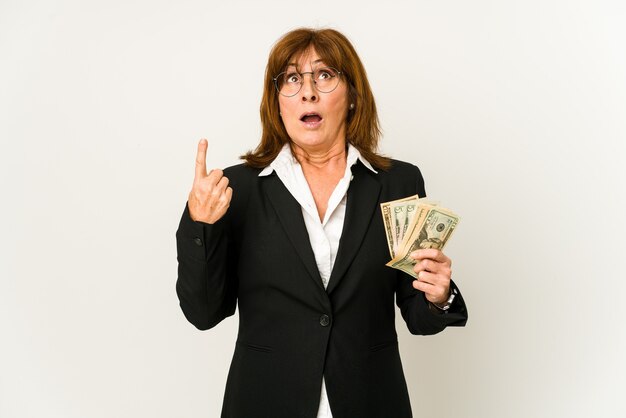 Middle age caucasian business woman holding banknotes isolated pointing upside with opened mouth.