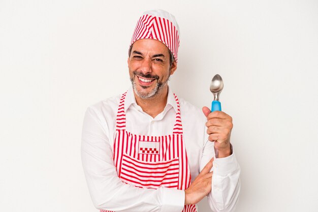 Middle age caucasian ice maker caucasian man holding a spoon isolated on white background  laughing and having fun.