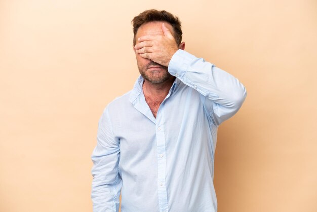 Middle age caucasian man isolated on beige background covering eyes by hands Do not want to see something