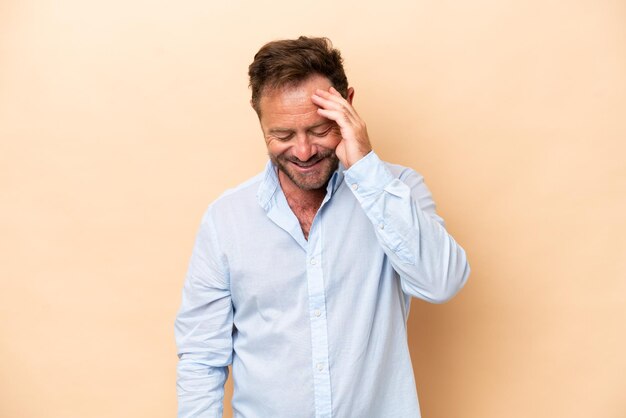 Middle age caucasian man isolated on beige background laughing