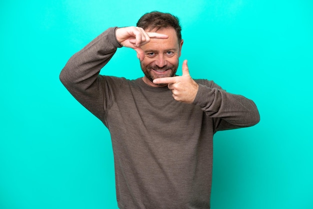 Middle age caucasian man isolated on blue background focusing face Framing symbol