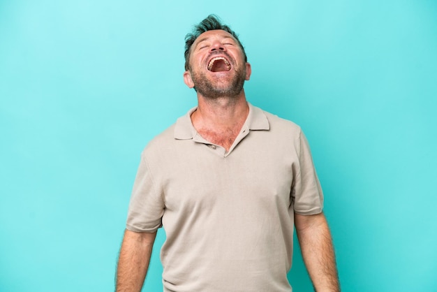 Middle age caucasian man isolated on blue background laughing