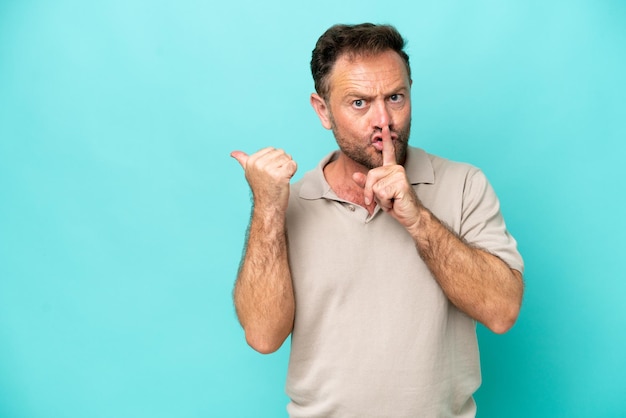 Middle age caucasian man isolated on blue background pointing to the side and doing silence gesture
