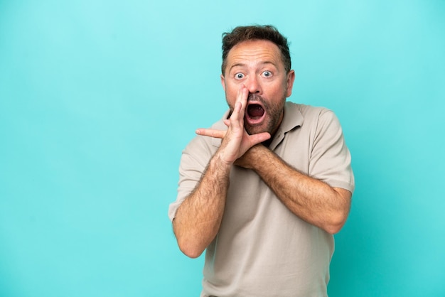 Middle age caucasian man isolated on blue background pointing to the side to present a product and whispering something