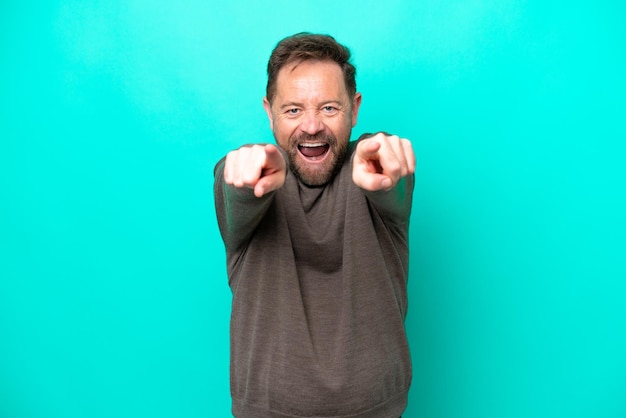 Middle age caucasian man isolated on blue background surprised and pointing front